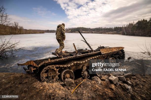 Ukrainian serviceman stands near a destroyed Russian tank in the northeastern city of Trostyanets', on March 29, 2022. - Ukraine said on March 26,...