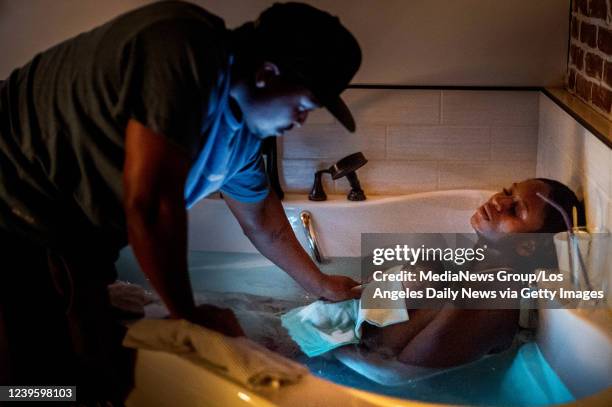 While Aysha-Samon Stokes rests, her partner Dennis Richmond touches their son after catching their baby in the birthing bath on Mothers Day night,...