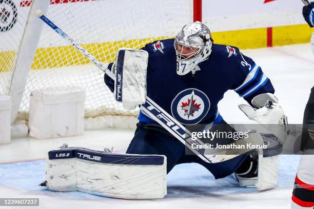 Goaltender Connor Hellebuyck of the Winnipeg Jets reacts a shot during second period action against the Ottawa Senators at Canada Life Centre on...