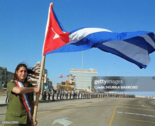 Woman holds a Cuban flag in front of the Office of US Interests in Havana 14 January 2000 during protests for the return of Elian Gonzalez, 6 yrs...