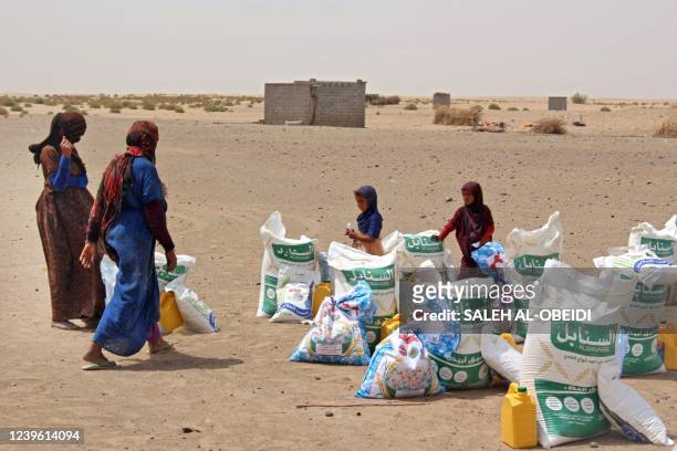 Poor Yemeni families receive flour rations and other basic food supplies from charities in the province of Lahj, in southern Yemen, on March 29 as...