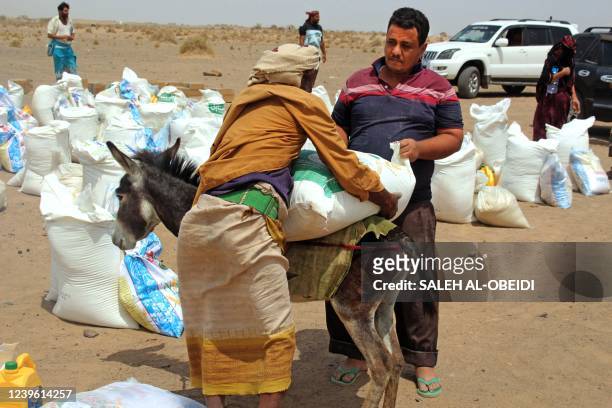 Poor Yemeni families receive flour rations and other basic food supplies like rice, oil and sugar, from charities in the province of Lahj, in...