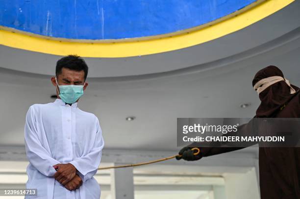 Man reacts as he is being punished by a sharia policeman for being caught in close proximity with a woman in Banda Aceh on March, 2022.