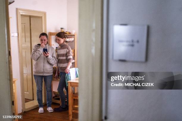 Olga Shandyba and another woman who fled Ukraine watch a mobile phone as they stand in a small flat at the Becov nad Teplou castle complex, where...