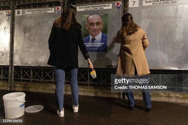 Supporters of Media pundit and French far-right party "Reconquete" presidential candidate Eric Zemmour, paste the official campaign poster for the...