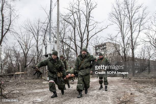 Soldiers of the DNR run with a stretcher carrying an injured separatist in a contested area of Mariupol. The battle between Russian / Pro Russian...