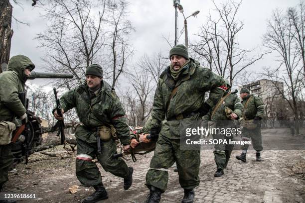 Soldiers of the DNR run with a stretcher carrying an injured separatist in a contested area of Mariupol. The battle between Russian / Pro Russian...