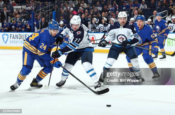 Dylan Cozens of the Buffalo Sabres battles for the puck against Adam Brooks of the Winnipeg Jets as Neal Pionk and Jeff Skinner look on during an NHL...