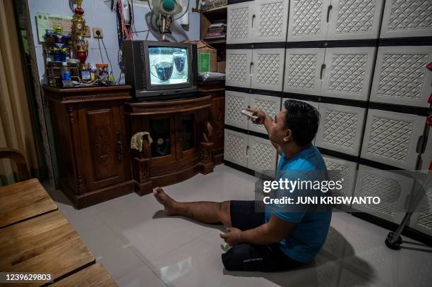This picture taken on March 23, 2022 shows disabled football player Syaiful Arifin watching television at his house in Surabaya. - Syaiful Arifin...
