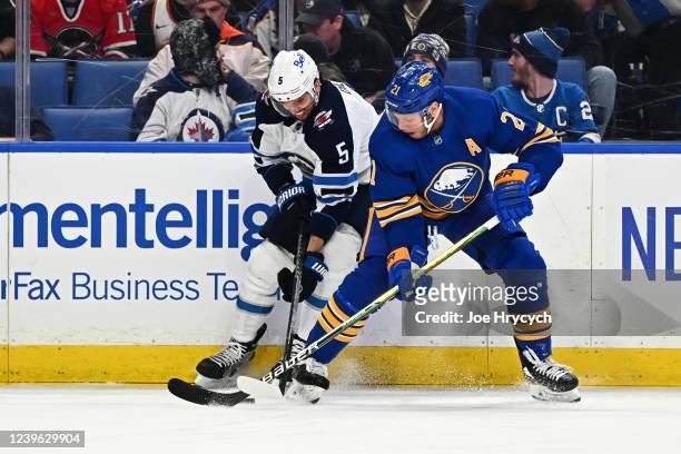 Kyle Okposo of the Buffalo Sabres battles for the puck against Brenden Dillon of the Winnipeg Jets during an NHL game on March 30, 2022 at KeyBank...