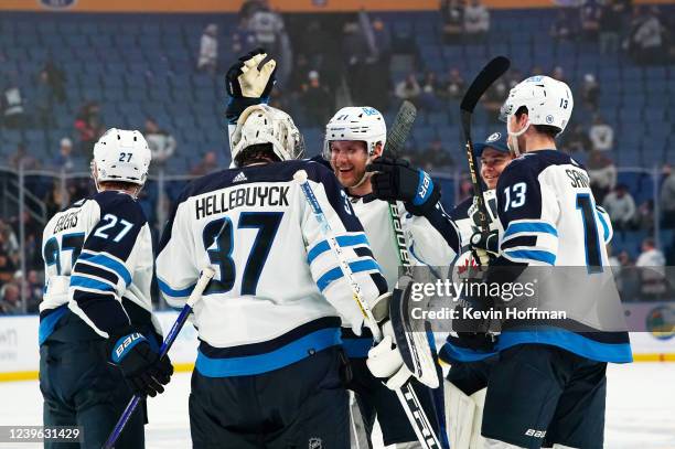 Connor Hellebuyck of the Winnipeg Jets celebrates with his team after beating the Buffalo Sabres in a shoot out at KeyBank Center on March 30, 2022...