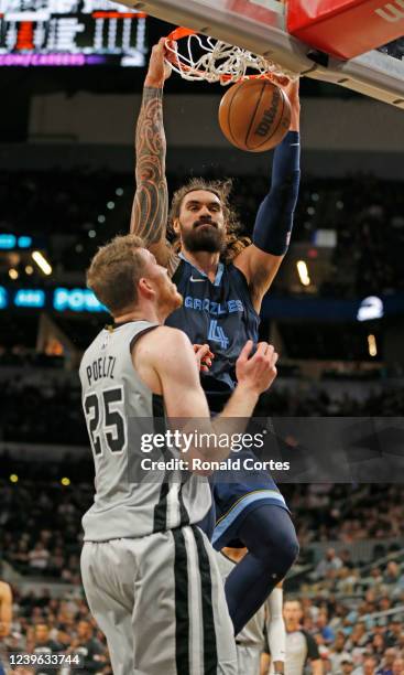 Jakob Poeltl of the San Antonio Spurs watches as Steven Adams of the Memphis Grizzlies dunks in the second half at AT&T Center on March 30, 2022 in...