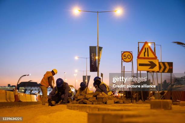 March 2022, Qatar, Doha: Workers pave a path between lanes on the Corniche promenade shortly after sunset in the light of lanterns. Doha will host...