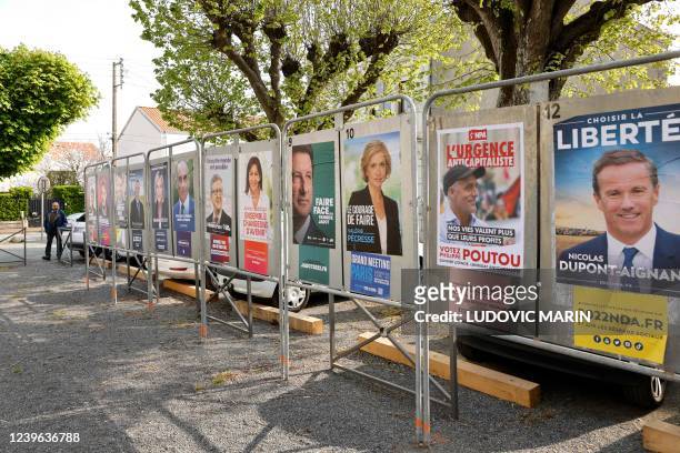 This photograph taken on March 31, 2022 shows official campaign posters of the twelve French presidential election candidates displayed in Fouras,...