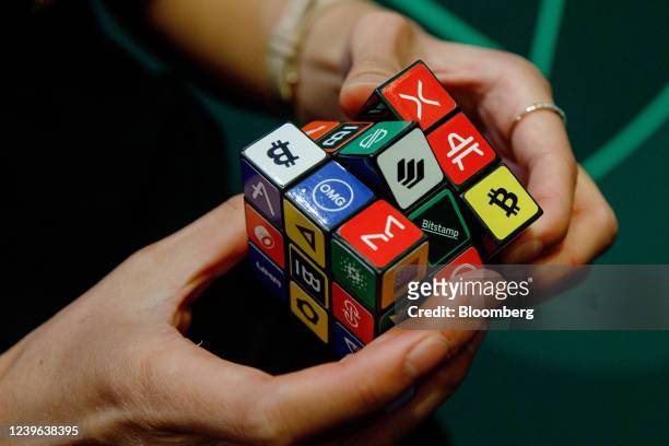 An attendee plays with a puzzle cube displaying logos of different cryptocurrencies and exchanges at the CryptoCompare Digital Asset Summit at Old...