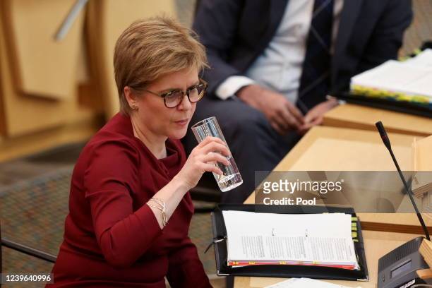 Scotland's First Minister Nicola Sturgeon holds a glass as she attends the First Minister's Questions at the parliament on March 31, 2022 in...