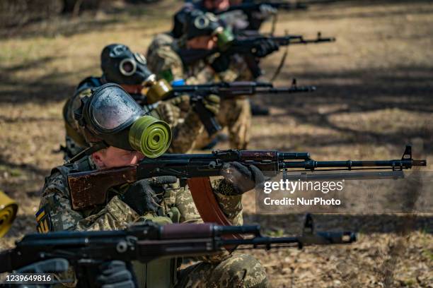 Civilian volunteers with chemical gas masks learn how to shoot with their their rifles in a military training in the forests of Zaporizhzhia,...