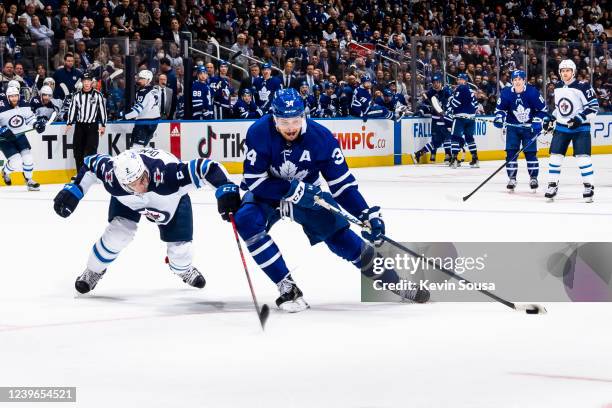 Auston Matthews of the Toronto Maple Leafs plays the puck against Dylan DeMelo of the Winnipeg Jets at Scotiabank Arena on March 31, 2022 in Toronto,...