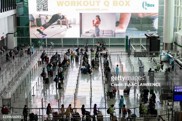Passengers line up to be taken to hotel quarantine at the Hong Kong International Airport on April 1 after the city lifted a flight ban on nine...