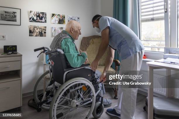 In this photo illustration an old man is helped into a wheelchair on March 30, 2022 in Heidelberg, Germany.