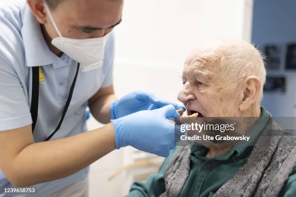 In this photo illustration a geriatric nurse helps to fix a denture in a mouth of a patient on March 30, 2022 in Heidelberg, Germany.