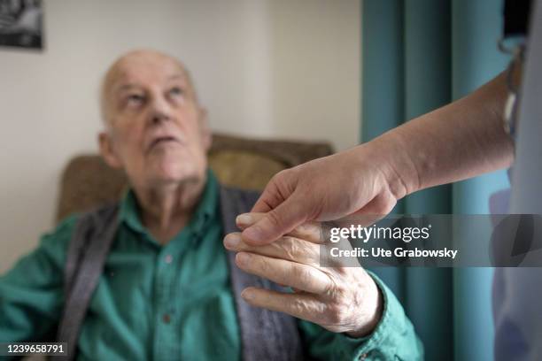 In this photo illustration a senior nurse holds hand of old man in nursing home on March 30, 2022 in Heidelberg, Germany.