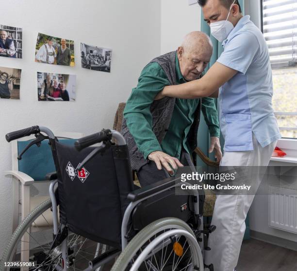 In this photo illustration an old man is helped into a wheelchair on March 30, 2022 in Heidelberg, Germany.