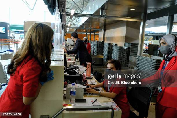 AirAsia staff at a counter at Kuala Lumpur International Airport 2 in Sepang, Selangor, Malaysia, on Friday, April 1, 2022. Malaysia allows...