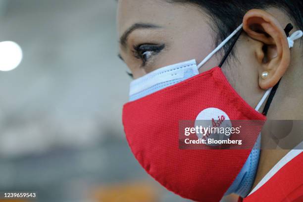 An AirAsia employee wears a protective mask with the company's logo at Kuala Lumpur International Airport 2 in Sepang, Selangor, Malaysia, on Friday,...