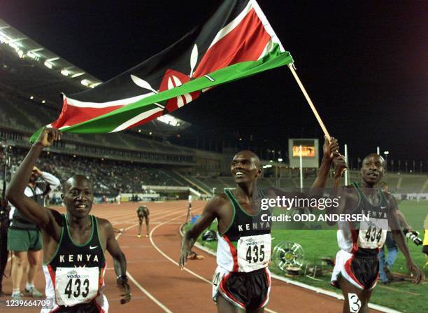 Kenyan Kipkurui Misoi holds the Kenyan flag aloft while celebrating with teammates Christopher Koskei and Wilson Boit Kipketer after winning the 3000...