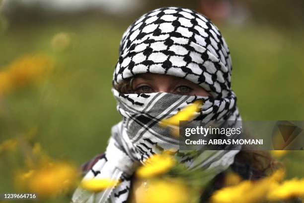 Palestinian protester wearing the traditional keffiyeh scarf as a mask takes part in a demonstration marking Land Day in Bilin village in the...
