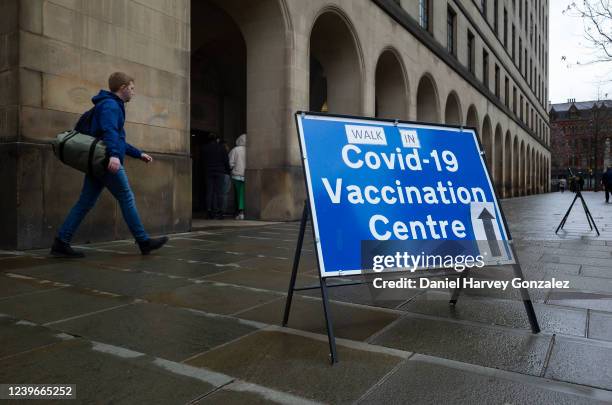 In bad weather, a member of the public passes by a sign advertising a walk-in Covid vaccination centre in the city as the Office for National...