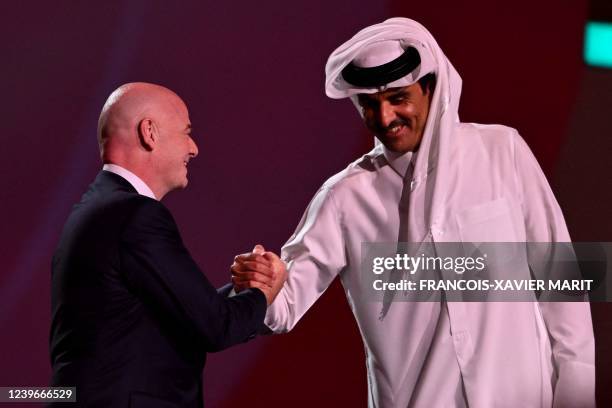 President Gianni Infantino shakes hands with Qatar's Emir Sheikh Tamim bin Hamad al-Thani on stage during the draw for the 2022 World Cup in Qatar at...