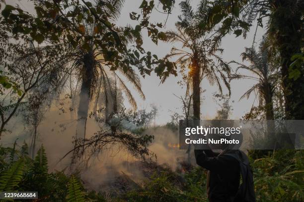 Women take picture a burning peat-land in Kampar, Riau Province, Indonesia.