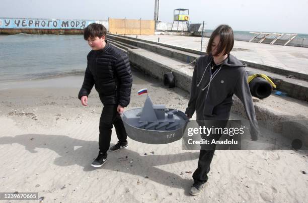 Ukrainian kids carry a metal ship made of buckets on the beach during an event dedicated to the April Fools' Day in Odessa, Ukraine on April 01, 2022.