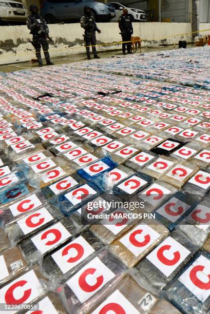Ecuadorean anti-narcotics police stand guard next to packs of cocaine from a 3-ton shipment seized from a container of bananas, in the port of...