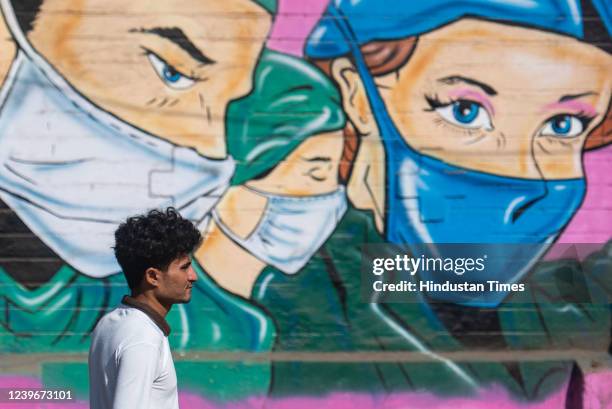 Man without a mask walks past a graffiti depicting people with masks, after State government lifts all Covid-19 restrictions on April 1, 2022 in...