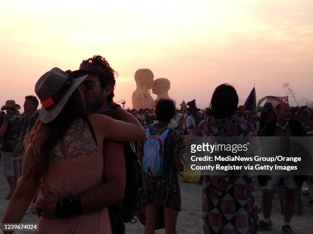 Black Rock Desert, NV Two burners share a kiss as the sun rises over Embrace, a wooden art installation that was burned Friday morning.