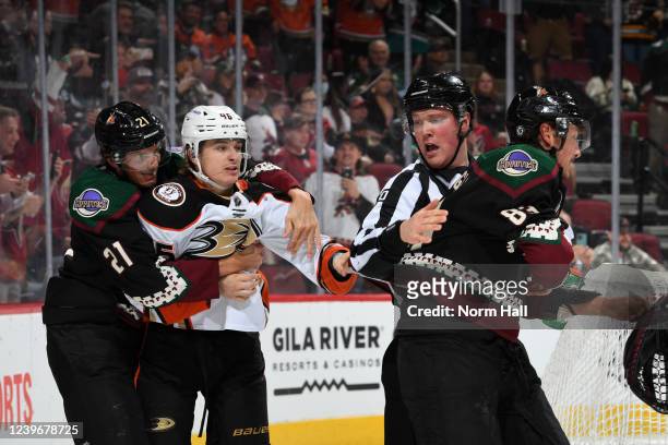 Trevor Zegras of the Anaheim Ducks grabs Jay Beagle of the Arizona Coyotes while being held back by Loui Eriksson as linesman Jonathan Deschamps...