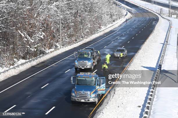 Tow truck drivers and a police officer are seen along closed southbound lanes of I-95 on Tuesday January 04, 2022 in Woodbridge, VA. Mondays snow...