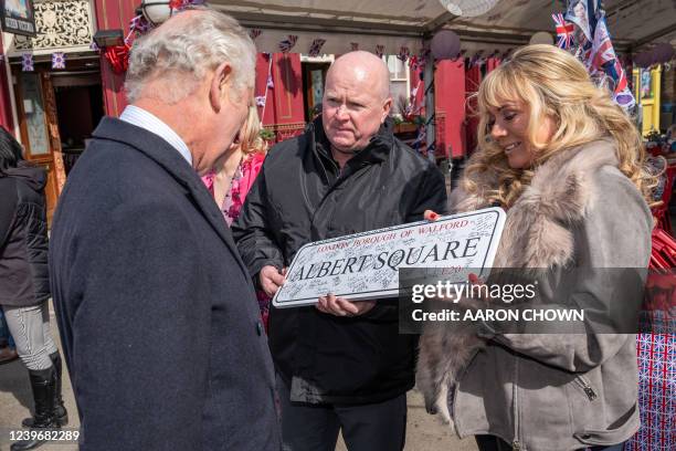 Britain's Prince Charles, Prince of Wales is presented with an Albert Square street sign by British actors Steve McFadden and Letitia Dean during a...