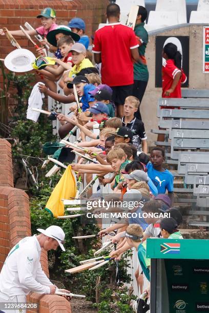 South Africa's Simon Harmer signs an autograph as kids line up during the third day of the first Test cricket match between South Africa and...