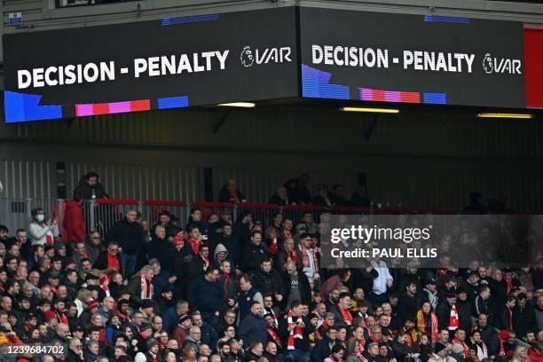 The big screens display the news that a VAR review has provided Liverpool with a late penalty during the English Premier League football match...