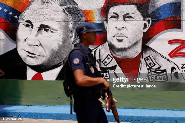 April 2022, Venezuela, Caracas: A man in Bolivarian National Police uniform walks next to a mural with the image of Vladimir Putin, president of...