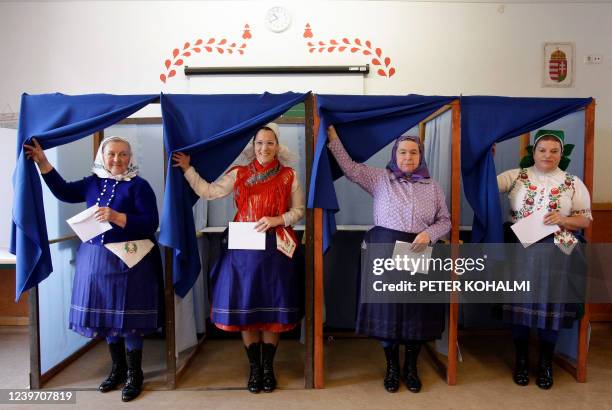 Women in traditional Hungarian dresses leave polling booths and prepare to cast their ballots at a polling station in a school in Veresegyhaz, some...