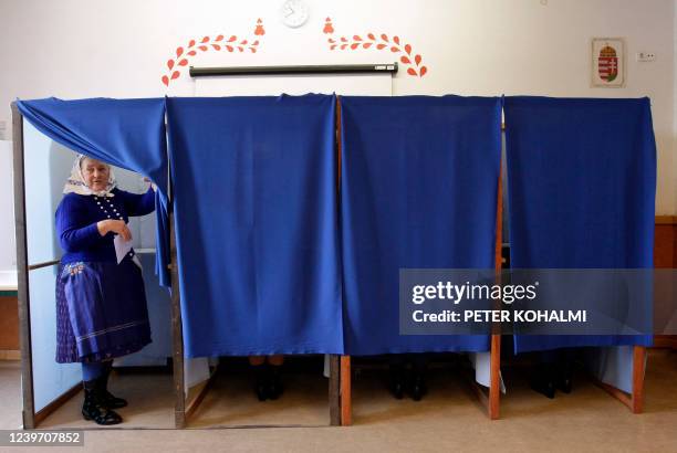 Women in traditional Hungarian dress leaves a polling booth and prepares to cast her ballot at a polling station in a school in Veresegyhaz, some...