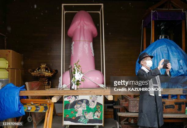 Man takes a picture in front of a large phallus-like statue stored in a warehouse at Kanayama Shrine in Kawasaki on April 3, 2022. Japanese revellers...
