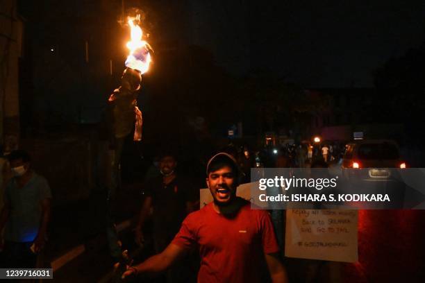 Protestors hold placards and torches during a demonstration against the surge in prices and shortage of fuel and other essential commodities in...