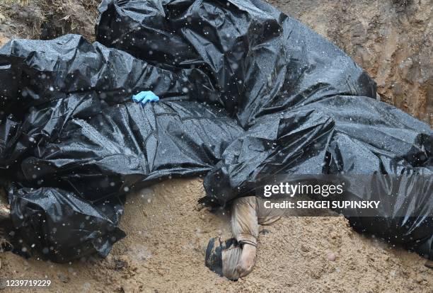 Partially buried body is seen in a mass grave in the town of Bucha, northwest of the Ukrainian capital Kyiv on April 3, 2022. - Ukraine and Western...