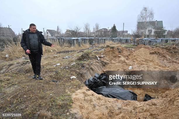 Man gestures at a mass grave in the town of Bucha, northwest of the Ukrainian capital Kyiv on April 3, 2022. - Ukraine and Western nations accused...